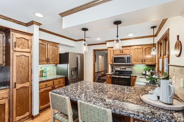 kitchen featuring pendant lighting, sink, ornamental molding, and stainless steel appliances