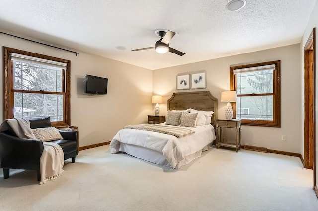 bedroom featuring ceiling fan, light colored carpet, and a textured ceiling