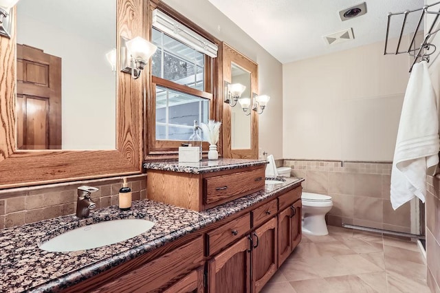 bathroom featuring vanity, tile walls, and toilet