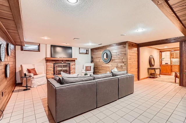 living room with a stone fireplace, light tile patterned floors, a textured ceiling, and wood walls