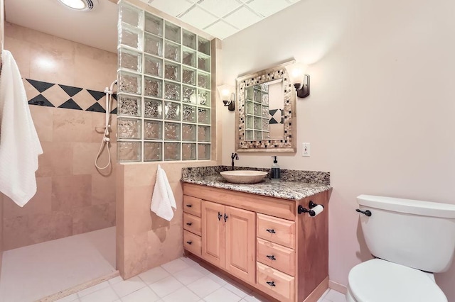 bathroom featuring vanity, a tile shower, and toilet