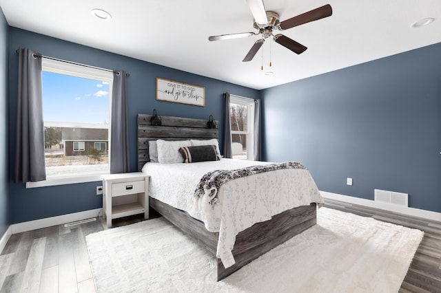 bedroom featuring multiple windows, wood-type flooring, and ceiling fan