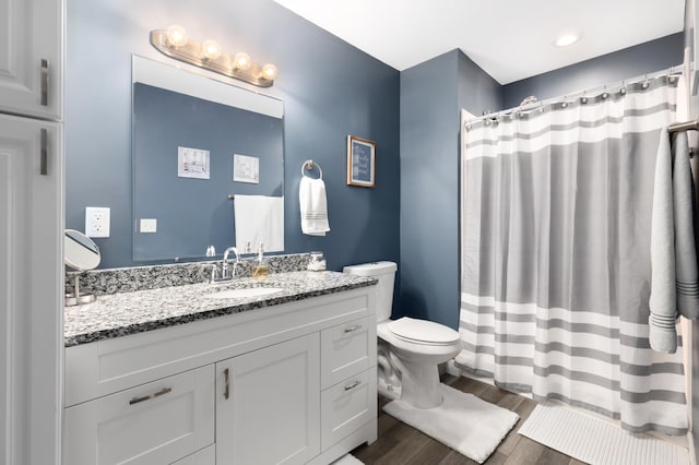 bathroom featuring wood-type flooring, toilet, a shower with shower curtain, and vanity