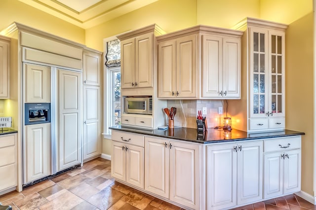 kitchen with decorative backsplash, cream cabinetry, and built in appliances