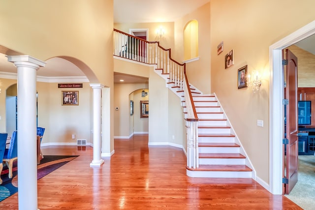 foyer entrance featuring ornate columns, crown molding, and wood-type flooring