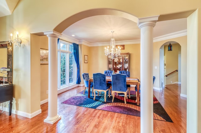 dining space featuring a chandelier, crown molding, light hardwood / wood-style floors, and decorative columns