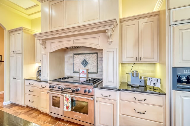 kitchen featuring high end range, custom range hood, cream cabinets, and tasteful backsplash