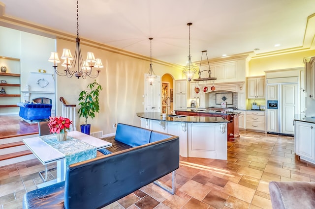 kitchen with cream cabinetry, built in features, pendant lighting, a chandelier, and crown molding