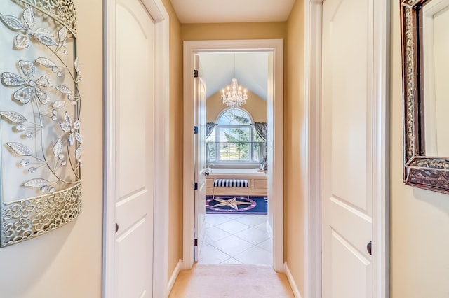 hallway with light tile patterned floors, vaulted ceiling, and an inviting chandelier