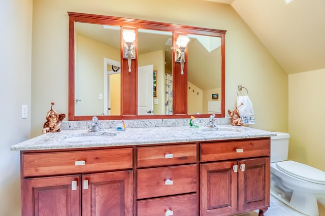 bathroom with toilet, vanity, lofted ceiling, and tile patterned flooring