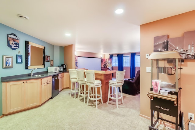 kitchen featuring black dishwasher, sink, a kitchen breakfast bar, kitchen peninsula, and light colored carpet