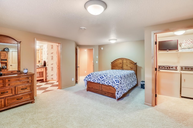 bedroom with light colored carpet, a textured ceiling, ensuite bathroom, and independent washer and dryer