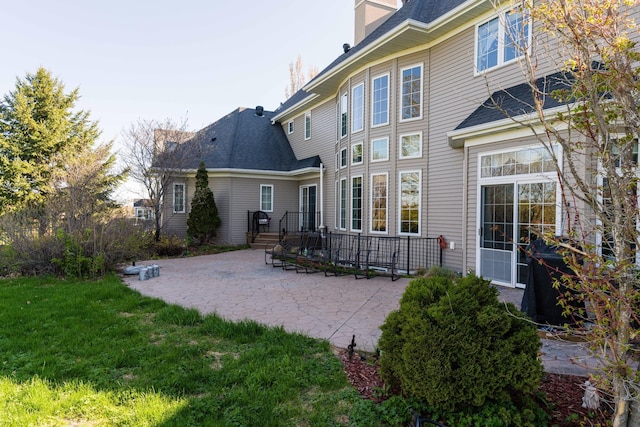 back of property with a yard and a patio