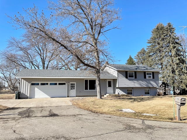 split level home featuring a garage, aphalt driveway, and a front yard