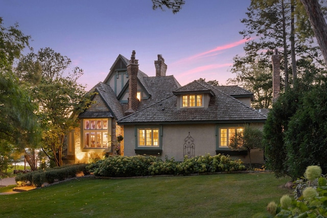 back house at dusk featuring a yard