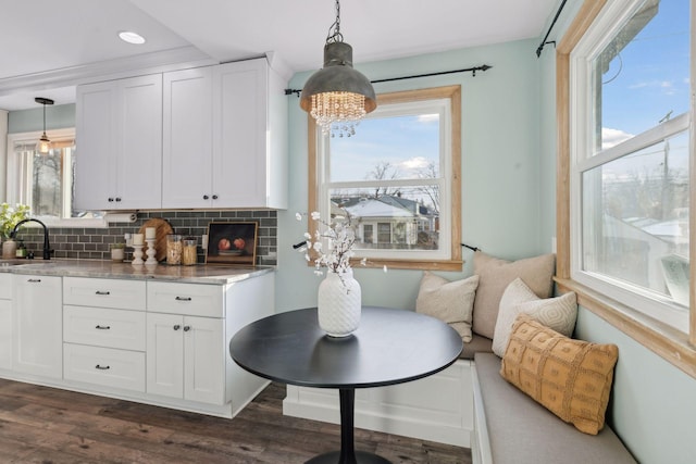 kitchen featuring decorative light fixtures, backsplash, white cabinets, and sink