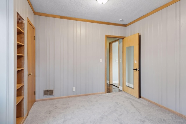 unfurnished room with carpet flooring, ornamental molding, and a textured ceiling