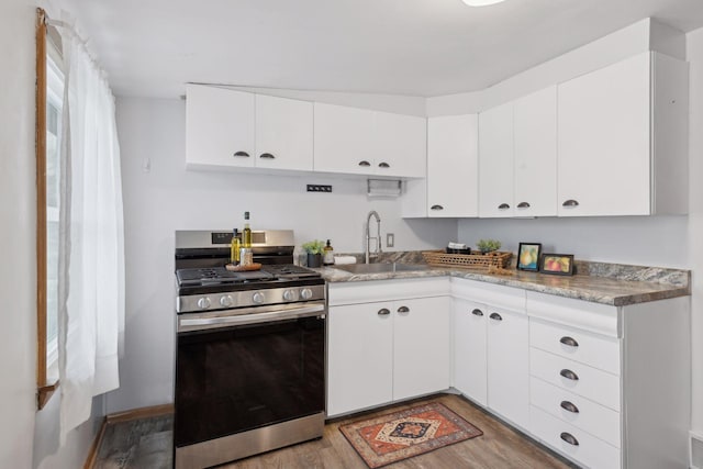 kitchen with gas range, sink, white cabinetry, and light hardwood / wood-style flooring