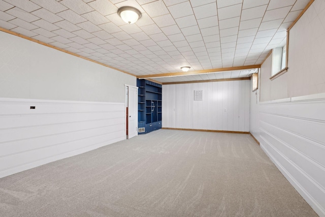 basement with crown molding and light colored carpet