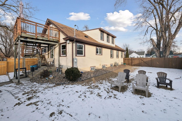 snow covered back of property with a wooden deck