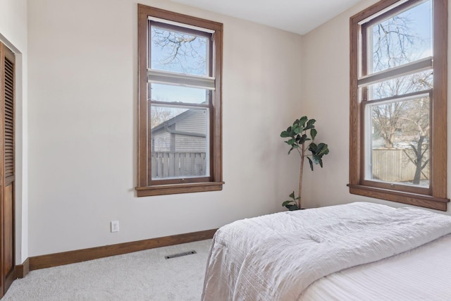 carpeted bedroom featuring multiple windows and a closet