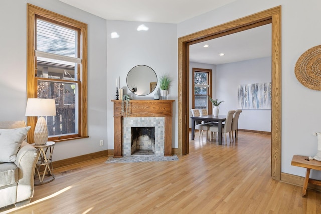 living room with a tiled fireplace and light hardwood / wood-style flooring