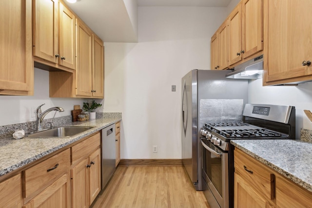 kitchen featuring appliances with stainless steel finishes, light brown cabinetry, sink, light stone counters, and light wood-type flooring