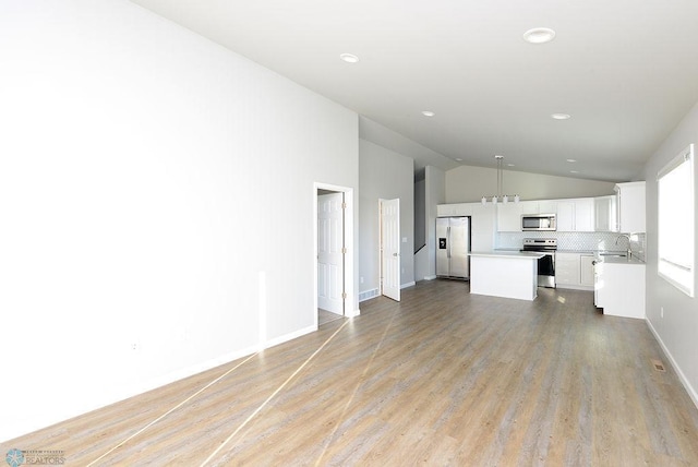 unfurnished living room with light hardwood / wood-style floors, vaulted ceiling, and sink