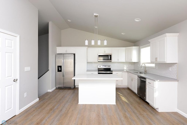 kitchen featuring a center island, sink, hanging light fixtures, stainless steel appliances, and vaulted ceiling