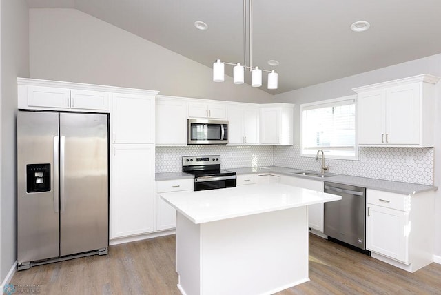 kitchen with a kitchen island, sink, light wood-type flooring, and stainless steel appliances