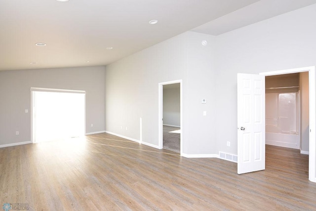 spare room featuring light hardwood / wood-style floors and lofted ceiling