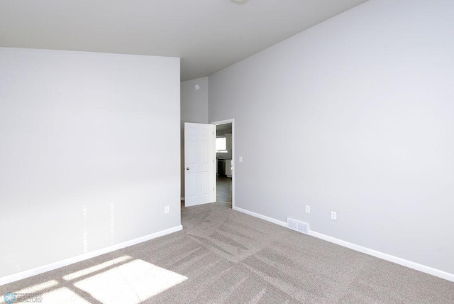 carpeted spare room with vaulted ceiling