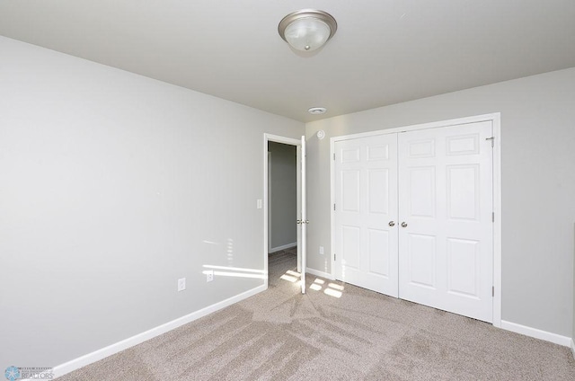 unfurnished bedroom featuring light carpet and a closet