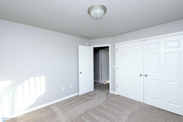 unfurnished bedroom featuring light colored carpet and a closet