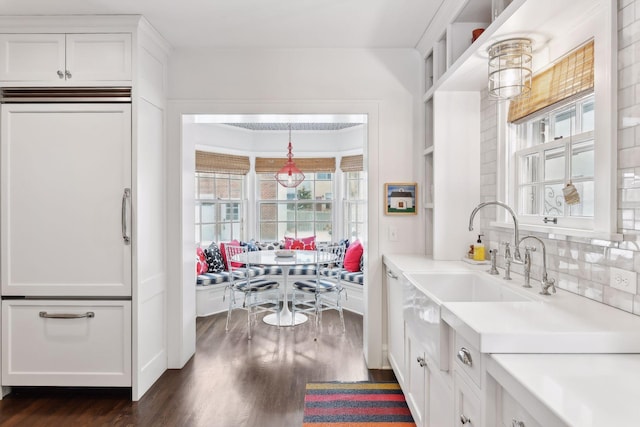 kitchen featuring dark hardwood / wood-style floors, sink, white cabinets, decorative backsplash, and hanging light fixtures