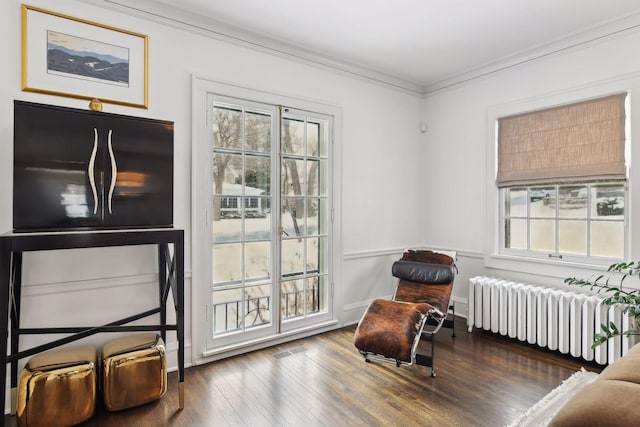 sitting room featuring ornamental molding, radiator heating unit, and hardwood / wood-style floors