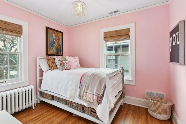 bedroom with radiator and hardwood / wood-style floors