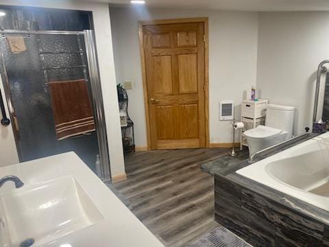 bathroom featuring hardwood / wood-style floors, tiled bath, toilet, and sink