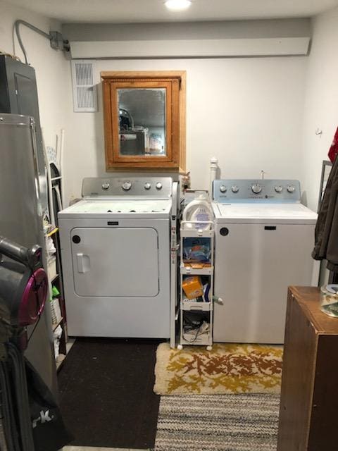 washroom with washing machine and clothes dryer, visible vents, and laundry area