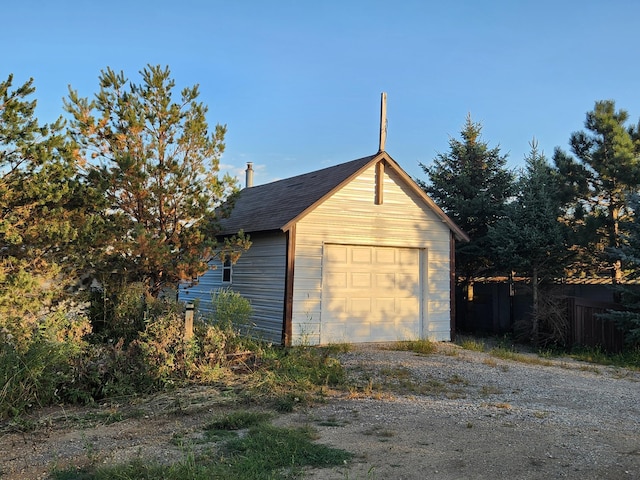 detached garage featuring fence and driveway