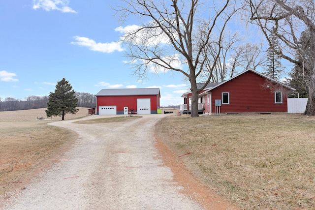 view of side of property with driveway, a garage, a lawn, and an outdoor structure