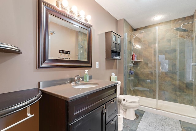 full bath with toilet, a shower stall, a textured ceiling, and vanity