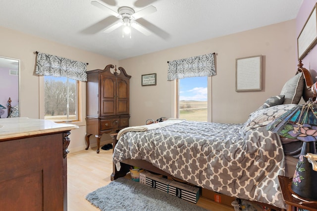 bedroom featuring light wood finished floors, ceiling fan, and a textured ceiling