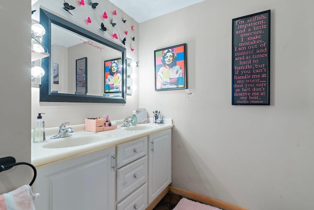 bathroom with double vanity, a sink, and baseboards