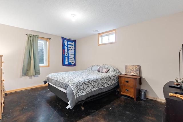 bedroom with concrete floors, a textured ceiling, and baseboards