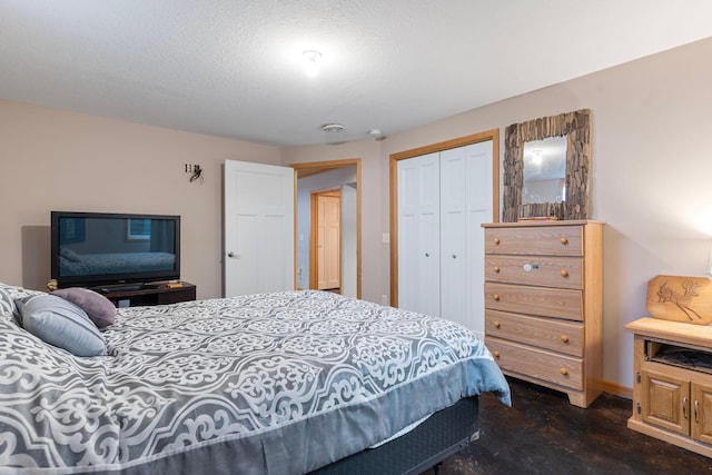 bedroom featuring a textured ceiling, finished concrete floors, baseboards, and a closet