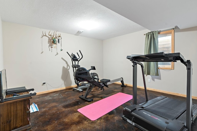 exercise area with a textured ceiling and baseboards