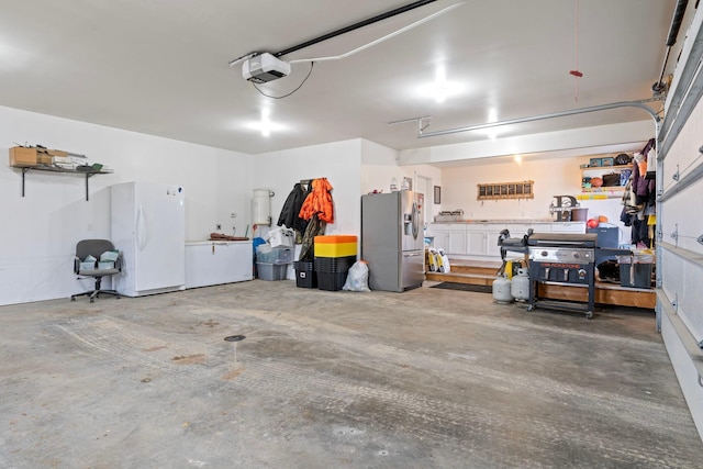 garage featuring a garage door opener, freestanding refrigerator, stainless steel refrigerator with ice dispenser, and a workshop area