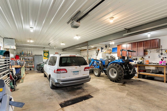 garage featuring a garage door opener, metal wall, and a workshop area