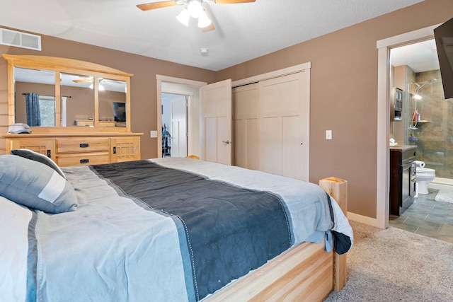 bedroom with a closet, carpet, baseboards, visible vents, and ensuite bathroom